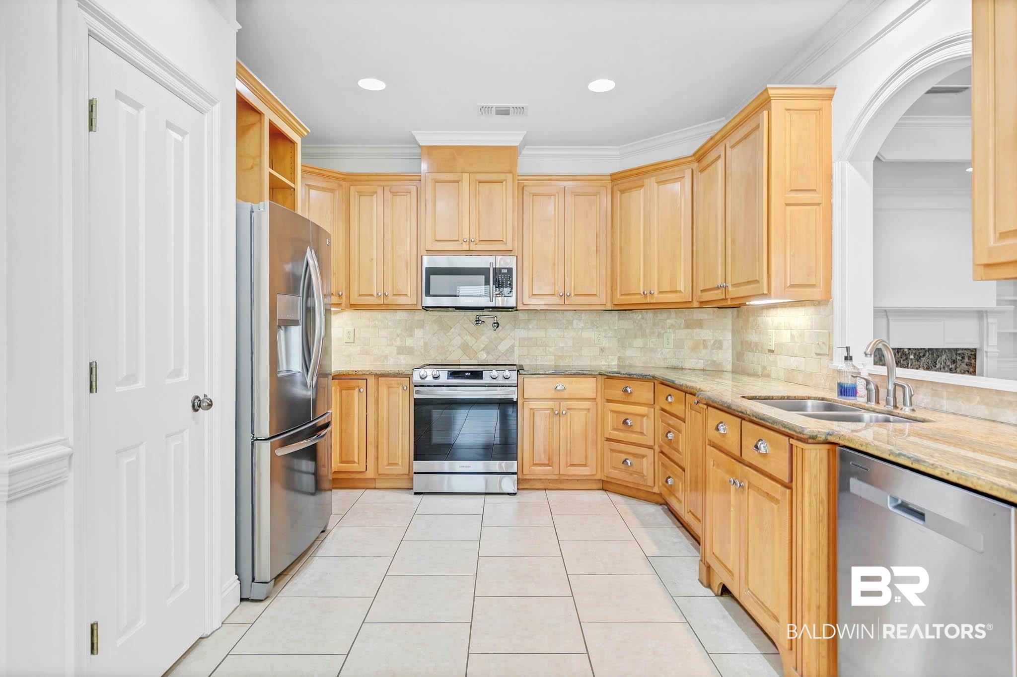 105 Cedar Pointe Fairhope, AL 36532 - Photo 16 of 38 Kitchen featuring light stone counters, appliances with stainless steel finishes, backsplash, light tile patterned floors, and light brown cabinets