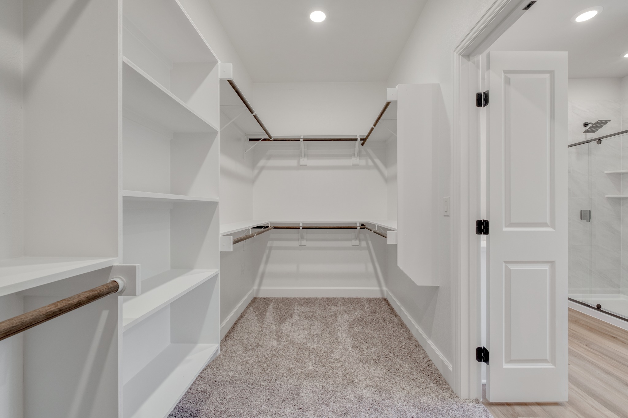 116 Pine Point Cove Elgin, TX 78621 - Photo 18 of 27 Walk-in closet featuring built-in shelving, multiple hanging rods, recessed lighting, and soft carpet flooring