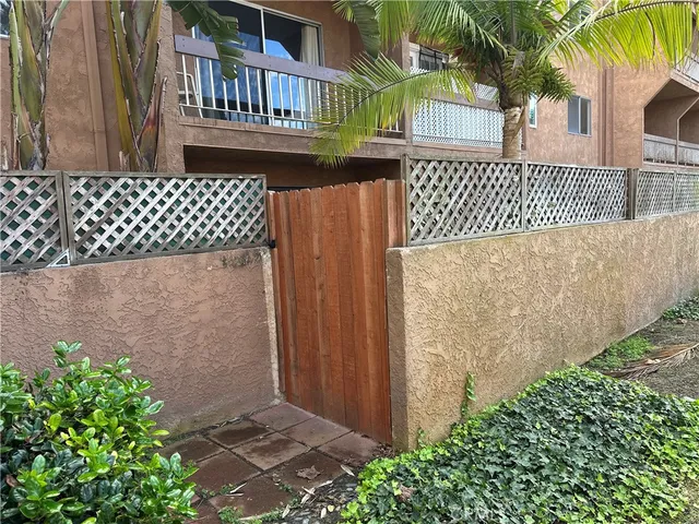 a view of a brick house with a small yard and wooden fence