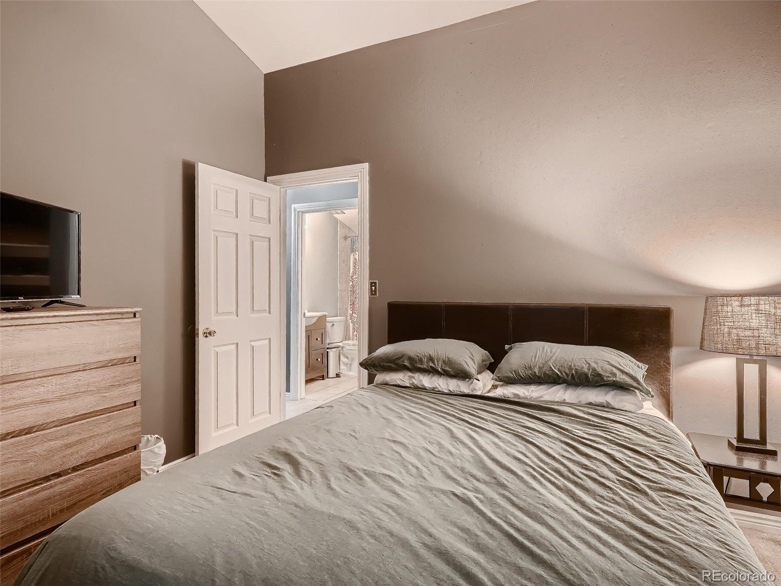 1230 South Reed Street, Unit 4 Lakewood, CO 80232 - Photo 18 of 28 a bedroom with a bed and flat tv screen on the dresser