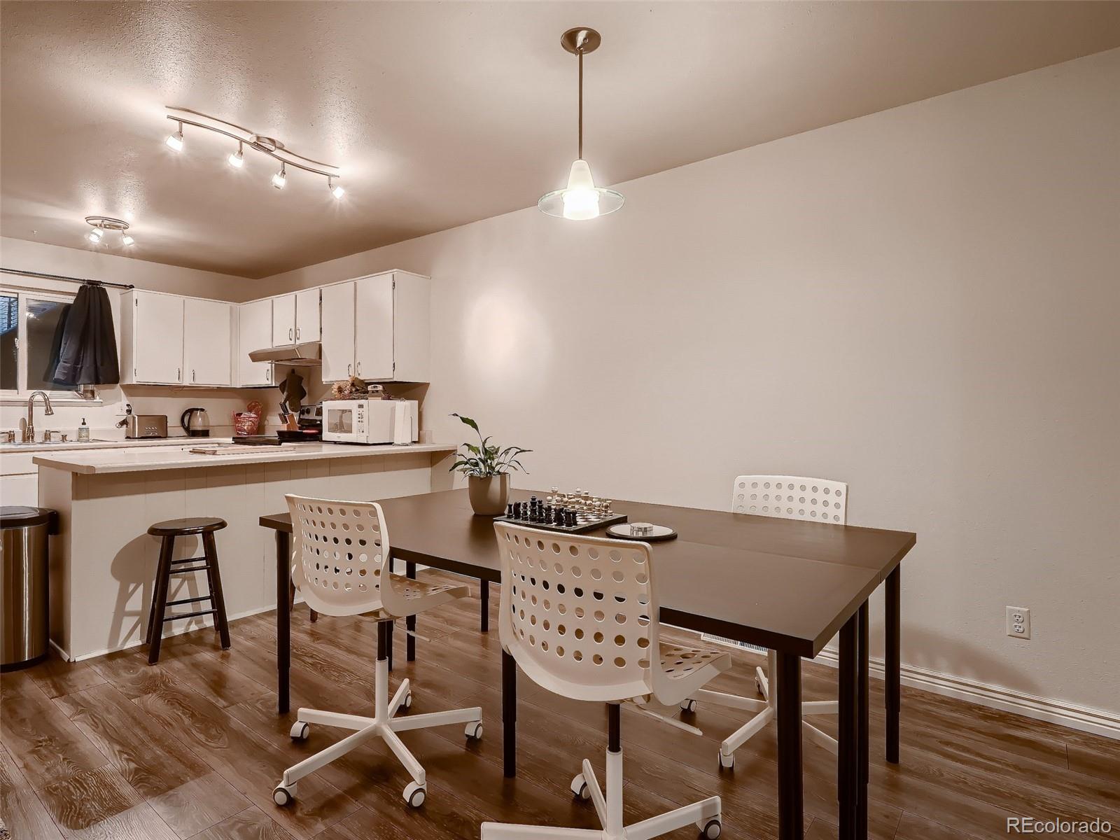 1230 South Reed Street, Unit 4 Lakewood, CO 80232 - Photo 7 of 28 a kitchen with stainless steel appliances granite countertop a dining table chairs a sink and dishwasher a refrigerator with wooden floor