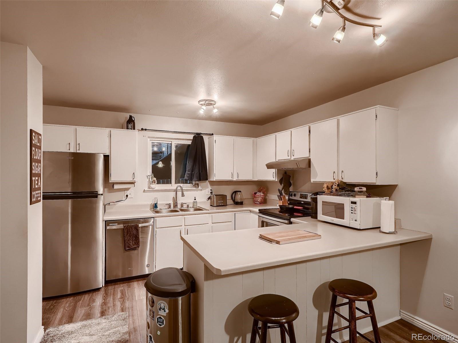 1230 South Reed Street, Unit 4 Lakewood, CO 80232 - Photo 9 of 28 a kitchen with a dining table chairs refrigerator and cabinets