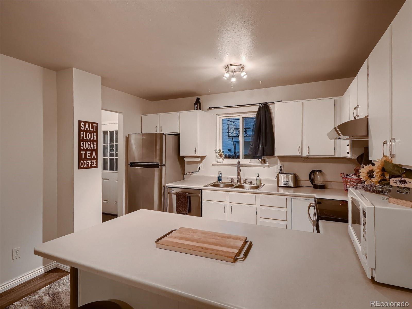 1230 South Reed Street, Unit 4 Lakewood, CO 80232 - Photo 10 of 28 a kitchen with white cabinets and stainless steel appliances