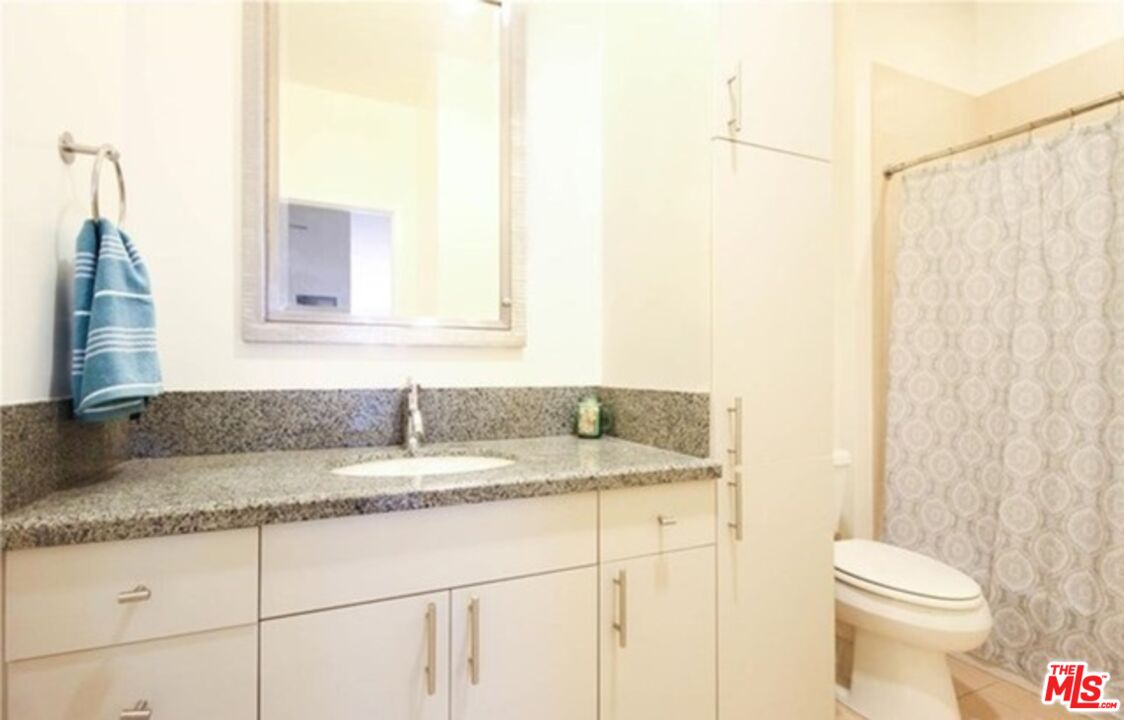 3810 Wilshire Boulevard, Unit 1004 Los Angeles, CA 90010 - Photo 13 of 14 a bathroom with a granite countertop sink and a mirror