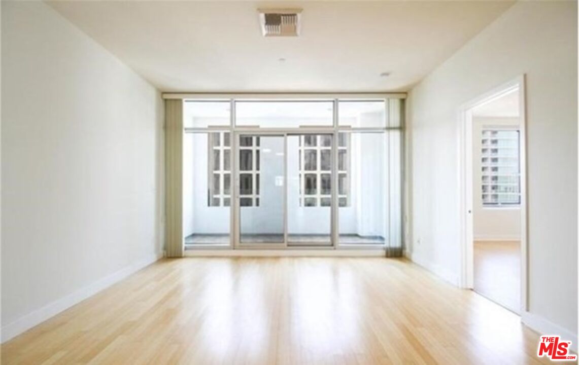 3810 Wilshire Boulevard, Unit 1004 Los Angeles, CA 90010 - Photo 8 of 14 an empty room with wooden floor and windows