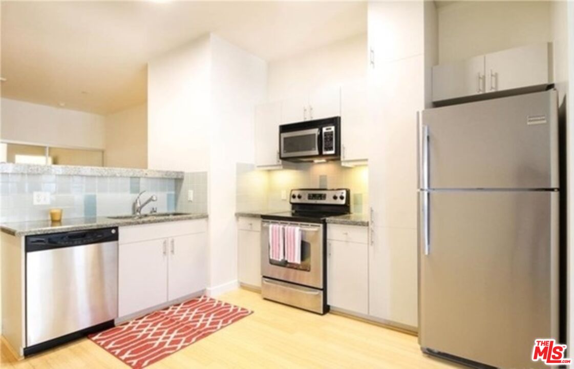 3810 Wilshire Boulevard, Unit 1004 Los Angeles, CA 90010 - Photo 9 of 14 a kitchen with stainless steel appliances granite countertop a refrigerator a stove a sink and a microwave