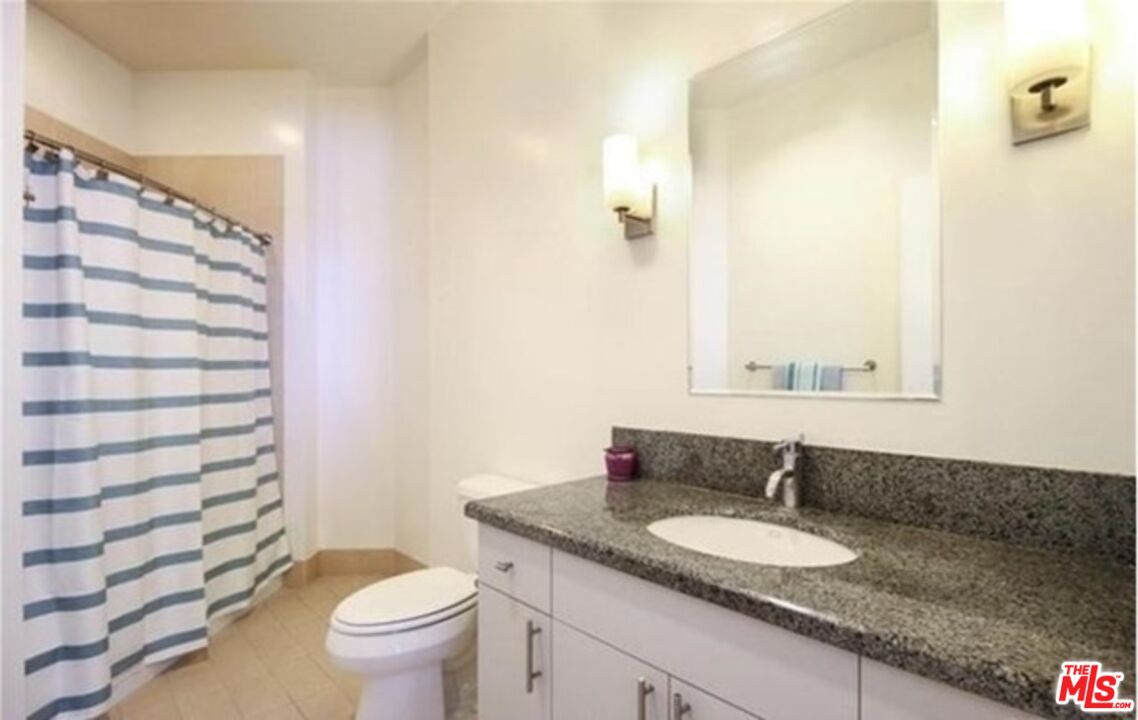 3810 Wilshire Boulevard, Unit 1004 Los Angeles, CA 90010 - Photo 10 of 14 a bathroom with a granite countertop sink a toilet and a mirror