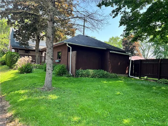 a backyard of a house with plants and large tree