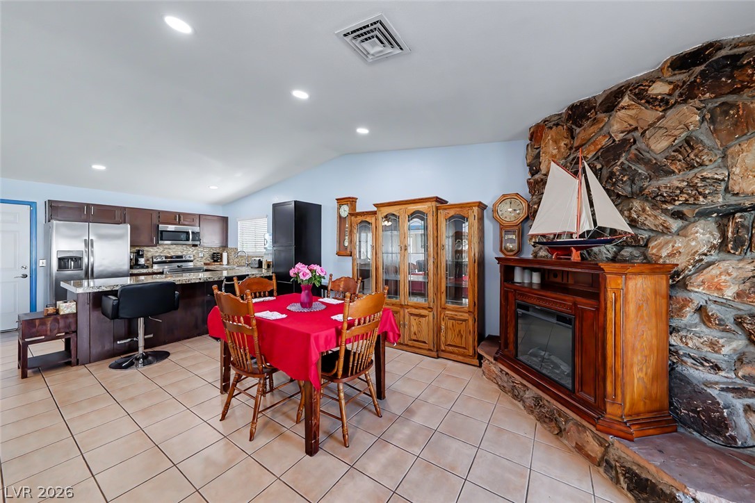 3107 Trueno Road Henderson, NV 89014 - Photo 12 of 37 A tiled dining area with an inviting stone fireplace adjoins a functional kitchen featuring ample counter space.