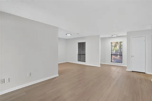 a view of an empty room with wooden floor and windows