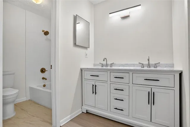 a bathroom with a granite countertop sink a toilet mirror and shower