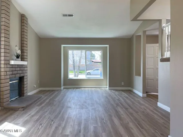 a view of a hallway with wooden floor and a living room