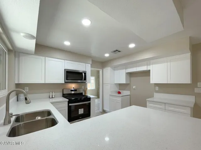 a large kitchen with stainless steel appliances granite countertop a refrigerator and a sink