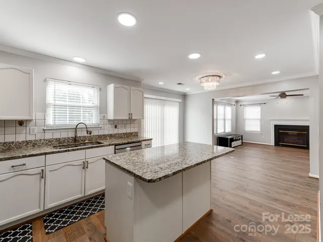 a kitchen with granite countertop a sink white cabinets and a stove