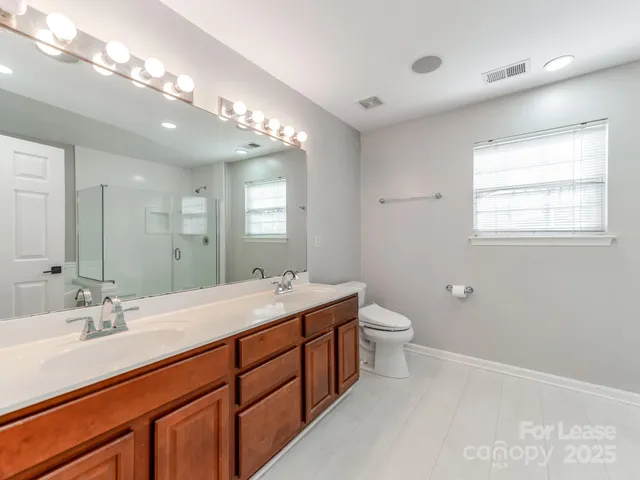 a spacious bathroom with a double vanity sink a toilet and a mirror
