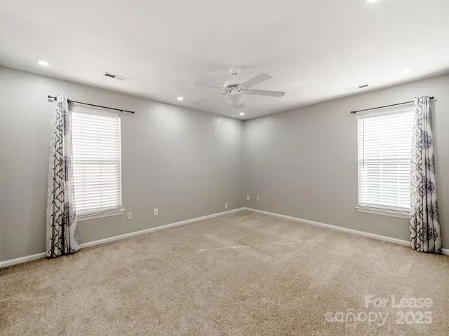 an empty room with windows and fan