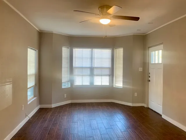 a view of an empty room with wooden floor and a window