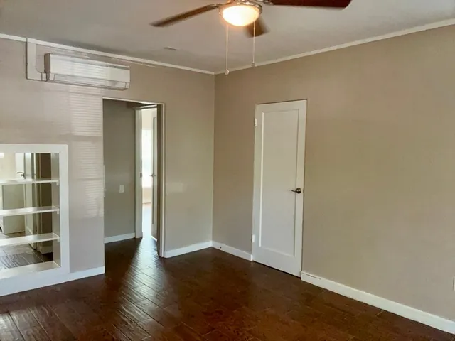 an empty room with wooden floor fan and windows