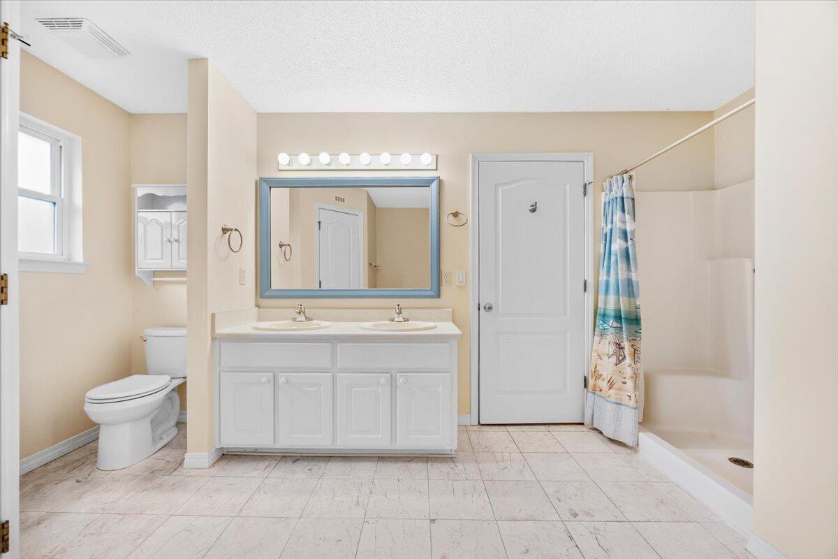 7807 Lola Circle Navarre, FL 32566 - Photo 25 of 45 a bathroom with a granite countertop sink a toilet and a mirror