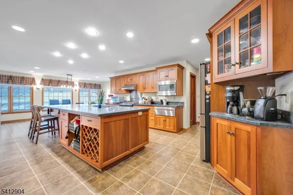 a open kitchen with stainless steel appliances granite countertop a refrigerator and wooden cabinets