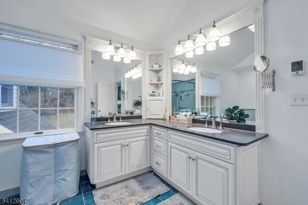 a kitchen with a sink dishwasher and white cabinets with wooden floor