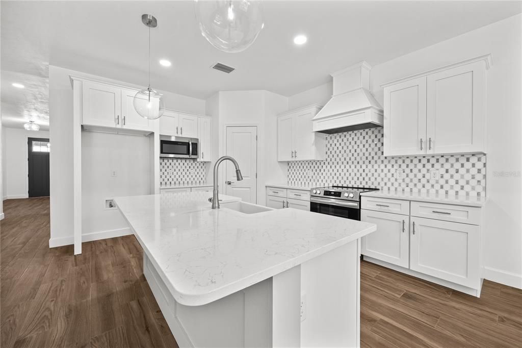 1086 Southwest 67th Drive Gainesville, FL 32607 - Photo 22 of 37 a kitchen with white cabinets appliances and wooden floor