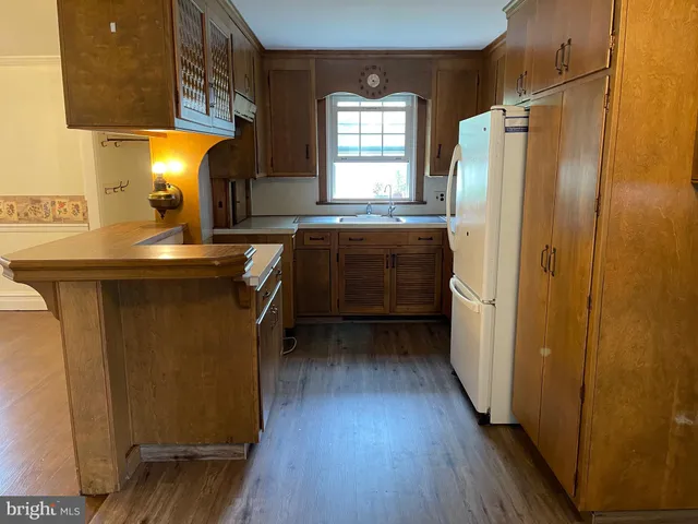 a kitchen with stainless steel appliances granite countertop a refrigerator a sink dishwasher a stove and white countertops with wooden floor