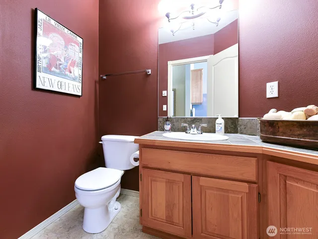 a bathroom with a granite countertop toilet sink and mirror