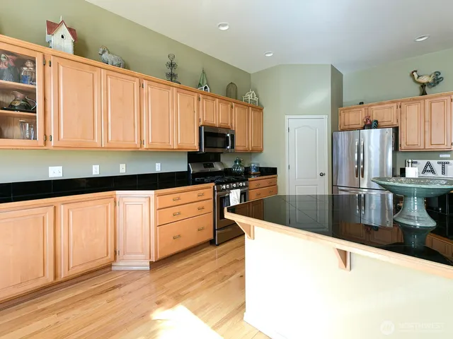 a kitchen with stainless steel appliances granite countertop a sink a stove and a refrigerator