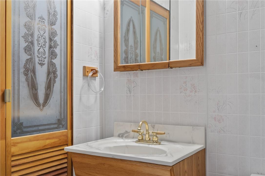 62 Stoney Road Tamaqua, PA 18252 - Photo 33 of 61 A well-maintained bathroom vanity with a gleaming brass faucet, set against neatly tiled walls.