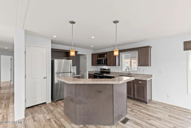 a kitchen with kitchen island a sink stainless steel appliances and white cabinets