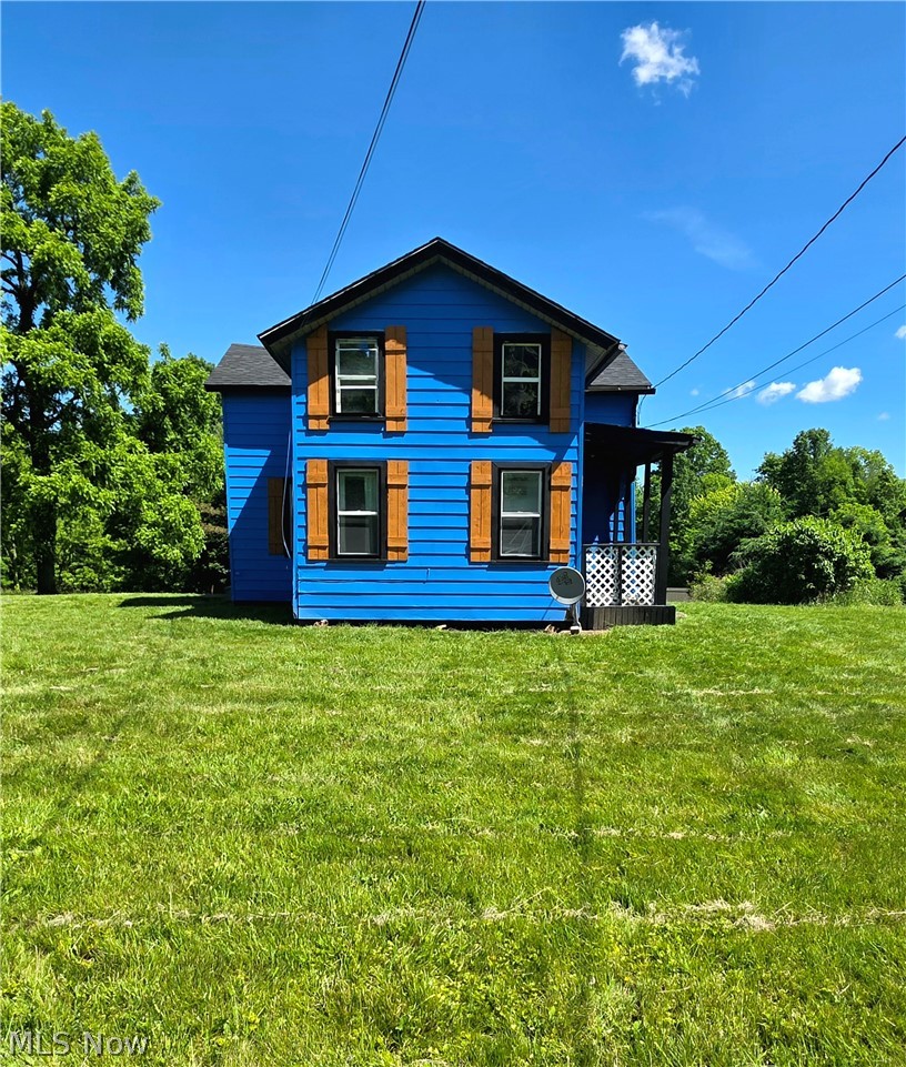 Exterior featuring blue siding, contrasting wood-finish shutters, and black-framed windows