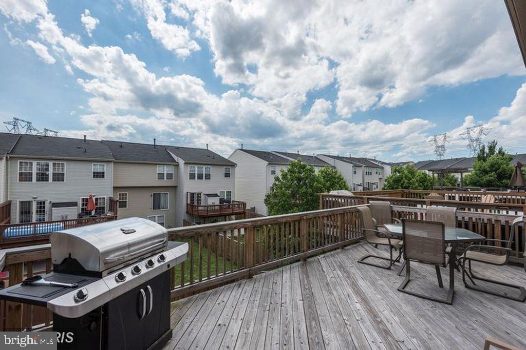 25259 Destination Square Aldie, VA 20105 - Photo 24 of 28 a view of a roof deck with table and chairs a barbeque with wooden floor and fence