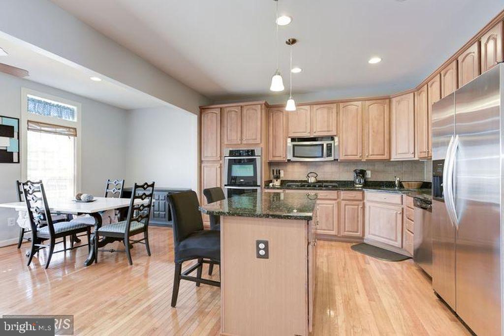 25259 Destination Square Aldie, VA 20105 - Photo 10 of 28 a kitchen with stainless steel appliances kitchen island granite countertop a table chairs microwave and sink