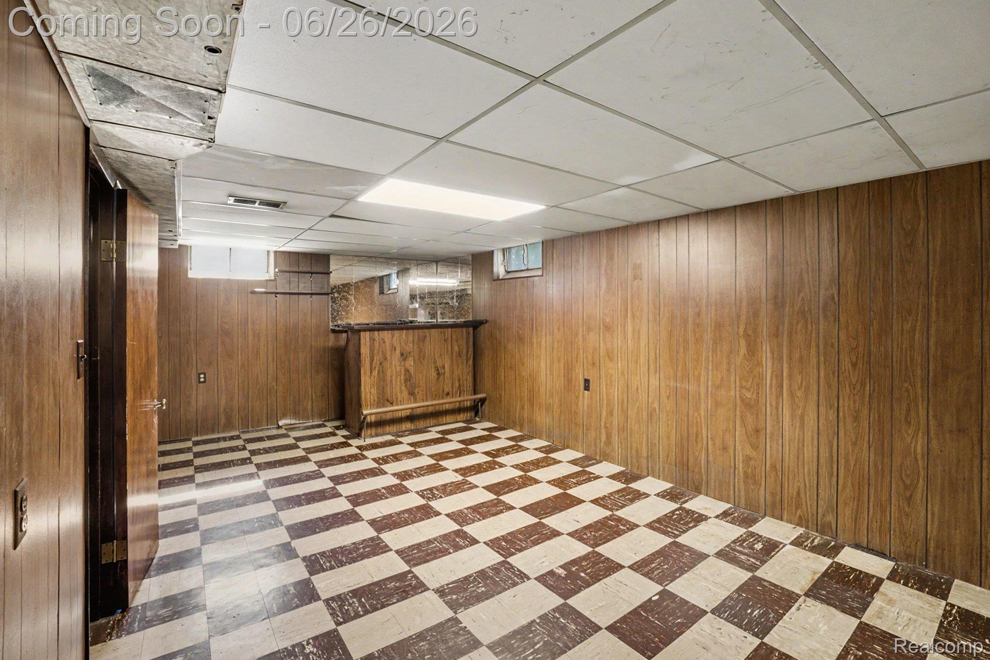 1209 Massoit Road Clawson, MI 48017 - Photo 20 of 25 Recreation room featuring wood-finish wall paneling, a built-in wet bar with a mirrored backsplash, and checkerboard flooring