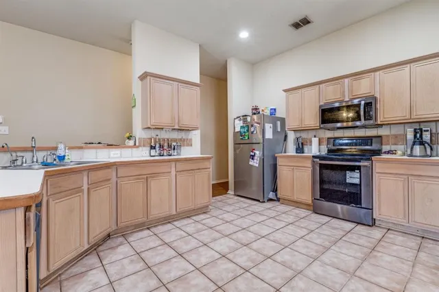 a kitchen with kitchen island granite countertop a sink window and stainless steel appliances