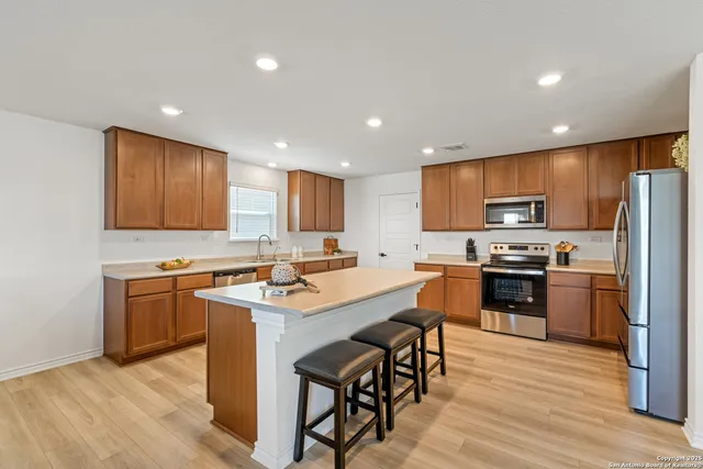 a kitchen with stainless steel appliances granite countertop wooden cabinets a refrigerator a stove a sink and a oven