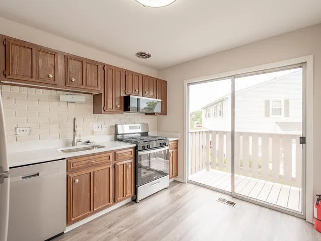 a kitchen with stainless steel appliances granite countertop a stove a sink dishwasher and a refrigerator with wooden cabinets