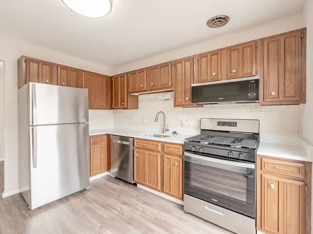 a kitchen with a refrigerator stove and wooden cabinets