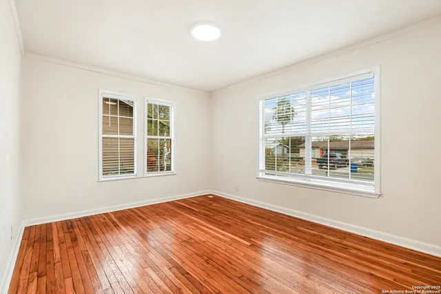a view of an empty room with wooden floor and a window
