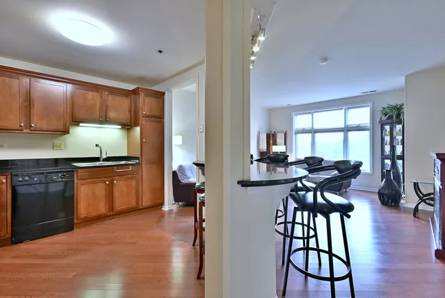 a kitchen with granite countertop a stove top oven a sink a dining table and chairs with wooden floor