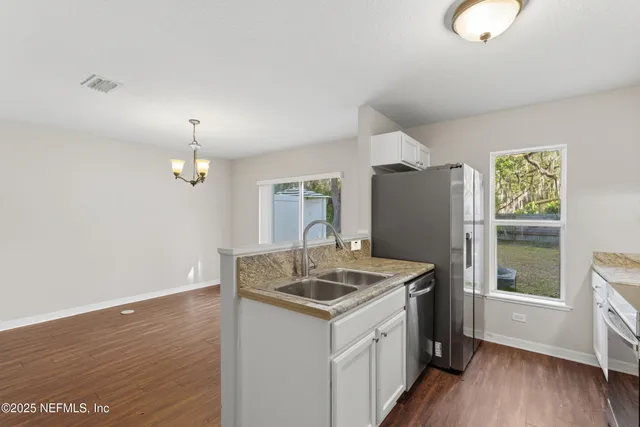 an empty room with windows and chandelier fan