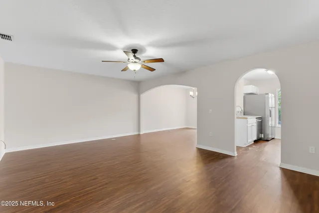 an empty room with wooden floor and ceiling fan
