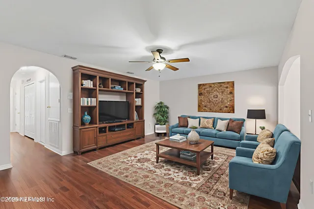 a view of an empty room with wooden floor and a ceiling fan