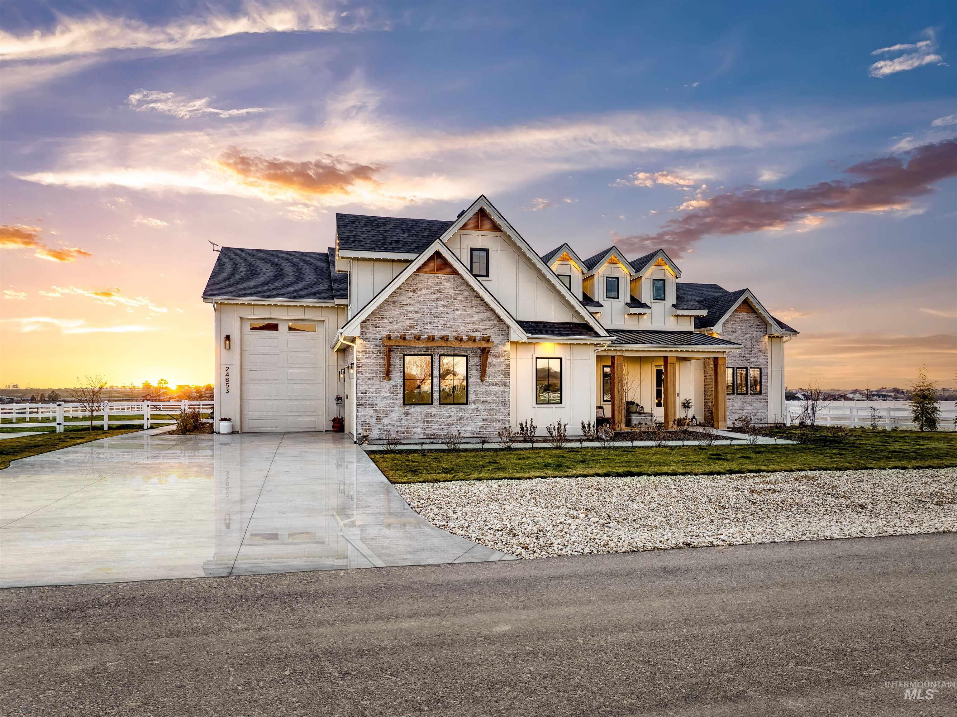 Modern farmhouse style home with board and batten siding, an attached garage, concrete driveway, a shingled roof, and stone siding