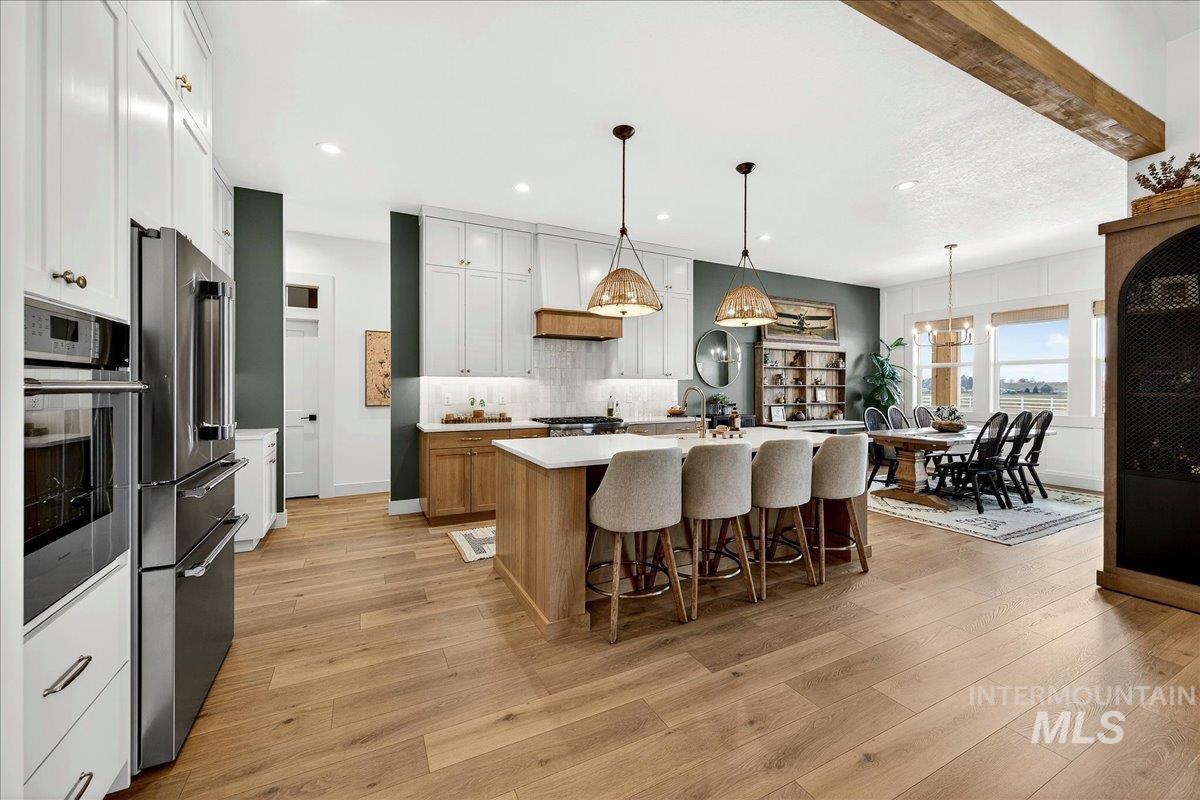 24853 Haflinger Way Middleton, ID 83644 - Photo 14 of 49 Kitchen with a center island with sink, dual tone cabinets, a kitchen bar, stainless steel appliances, and light wood-type flooring