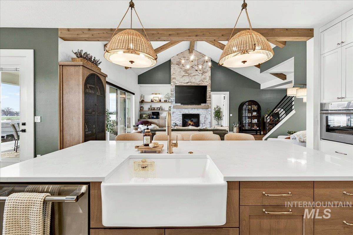 24853 Haflinger Way Middleton, ID 83644 - Photo 49 of 49 Kitchen with stainless steel appliances, open floor plan, a kitchen island with sink, a stone fireplace, and hanging light fixtures