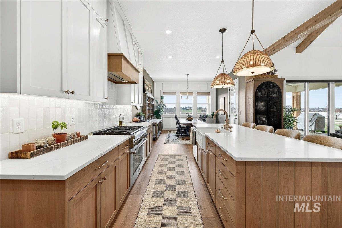 24853 Haflinger Way Middleton, ID 83644 - Photo 16 of 49 Kitchen featuring a large island, stainless steel stove, beam ceiling, two tone color scheme, and light wood finished floors