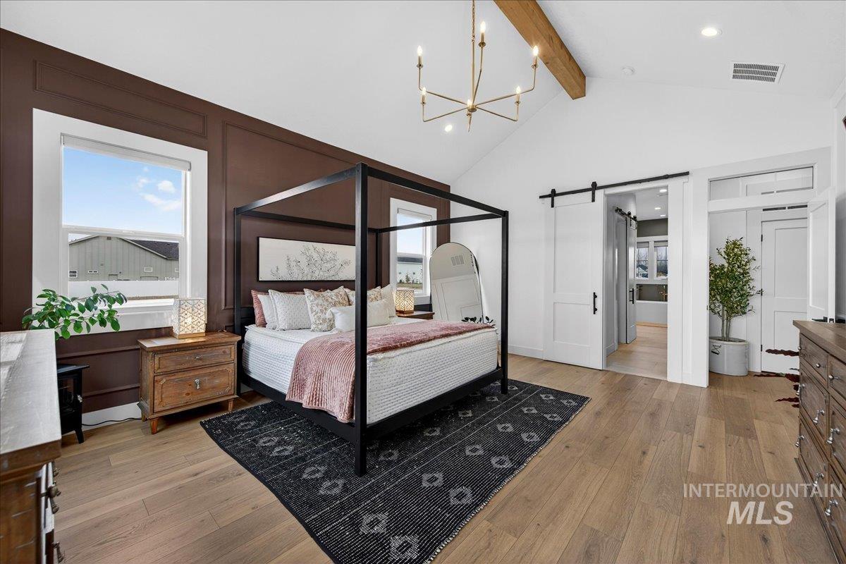 24853 Haflinger Way Middleton, ID 83644 - Photo 24 of 49 Bedroom with a barn door, light wood-type flooring, hanging lights, and multiple windows