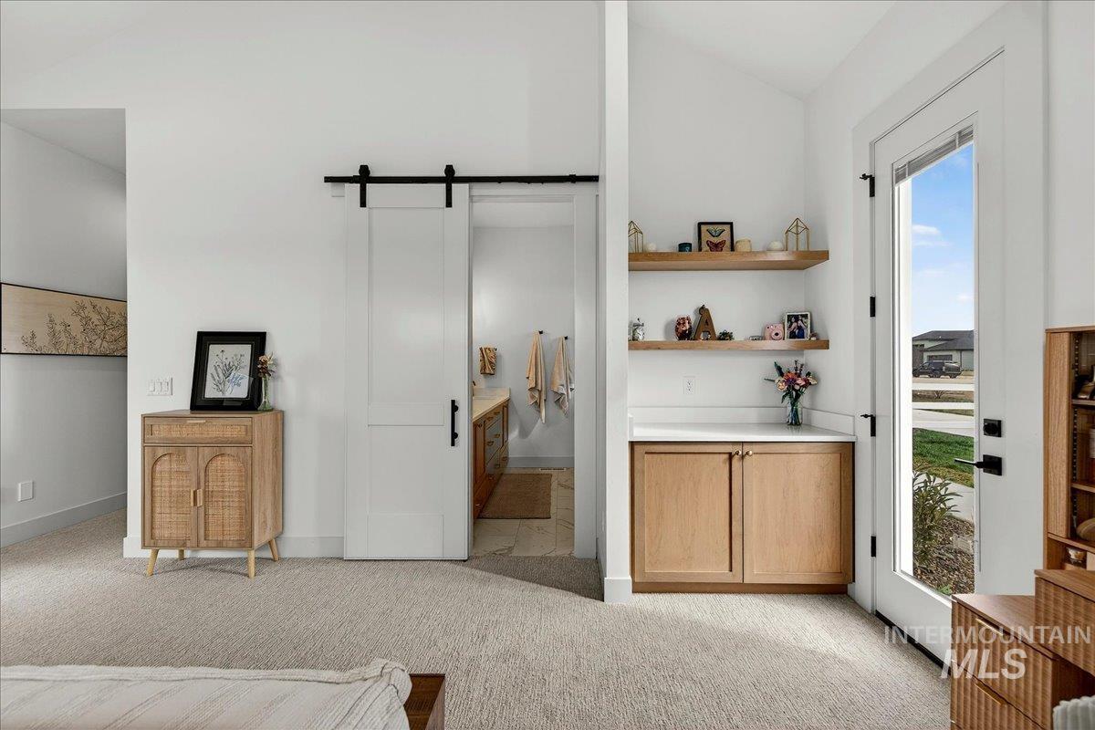 24853 Haflinger Way Middleton, ID 83644 - Photo 30 of 49 Bedroom with a barn door, vaulted ceiling, light carpet, access to outside, and ensuite bathroom